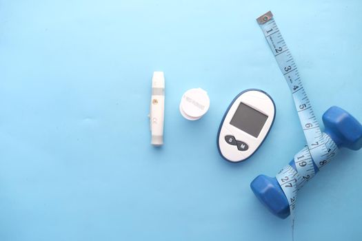 diabetic measurement tools and a dumbbell on blue background.