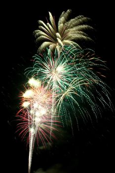 Image of Multicolored Fourth of July fireworks at night that are green and yellow and red and white