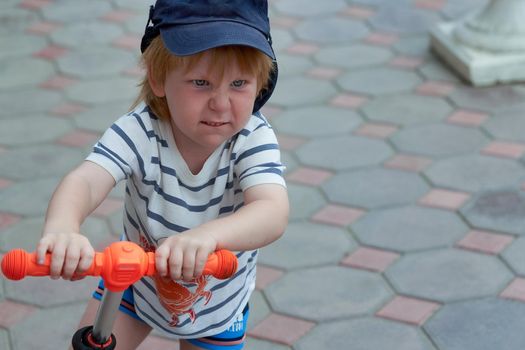 The face of a child with a bright emotion on the face of a scooter. Expressing the emotions of the child
