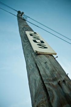 Image of Telephone pole with nails and a white sign with black letters that reads Jesus