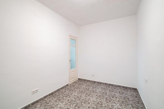 Room interior after renovation, unfurnished apartment with white walls, tiled floor and small door