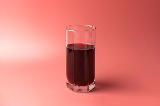 a glass of pomegranate juice on a red background. High quality photo