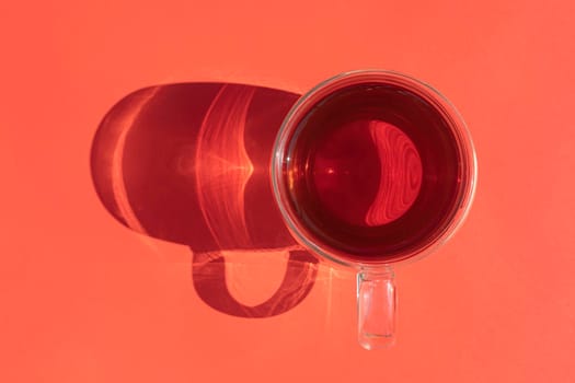 a mug of tea with a hard shadow on an red background. High quality photo