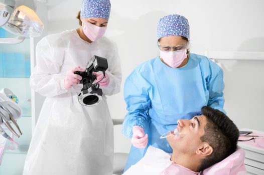 Dentist with camera making shots of beautiful young patient's smile. High quality photo.