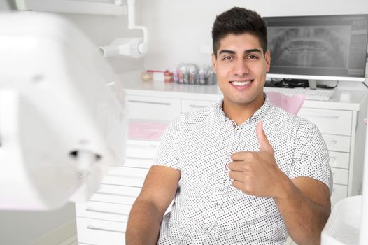Man giving thumbs up at dentist office. High quality photo