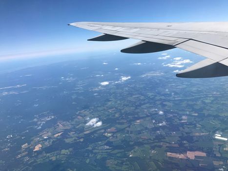 View from window of airplane wing over blue and green landscape