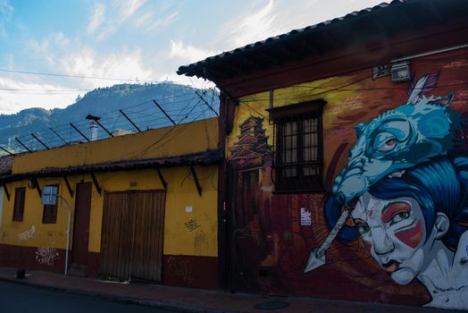 View of graffiti buildings in Bogota, Colombia with Mount Monserrate in background.