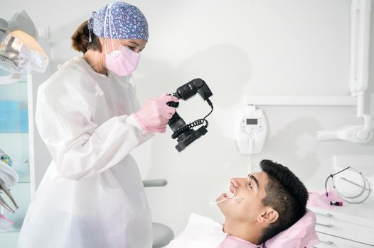 Dentist with camera making shots of beautiful young patient's smile. High quality photo.