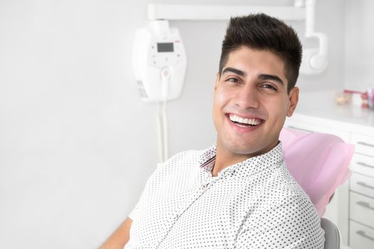 Portrait of a positive handsome patient smiling looking at camera, after treatment at dental clinic. High quality photo.