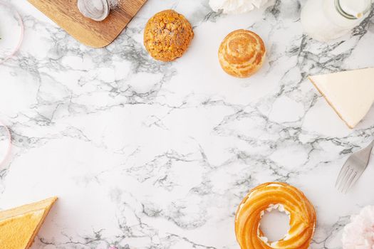 Homemade profitroles pastry filled with custard. Eclairs with cream, French dessert and flowers on marble table top view