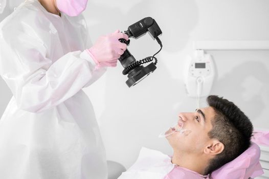 Dentist with camera making shots of beautiful young patient's smile. High quality photo.