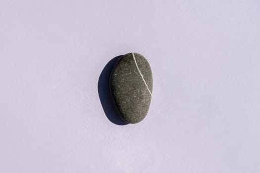 a stone with a hard shadow on a gray background. High quality photo