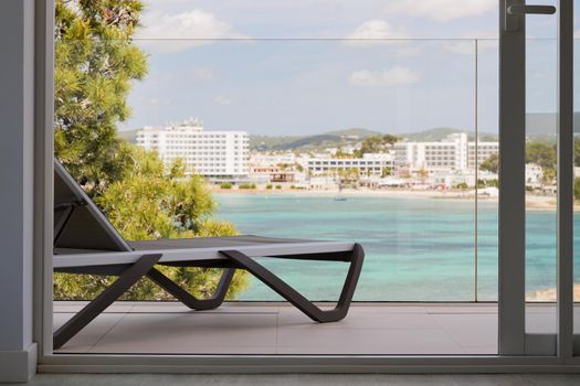 Sunbed on the terrace of an hotel with beautiful view on the sea and bay on Ibiza island.
