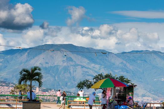 Tropical view with palm tree umbrella and puffy clouds over mountains in Bogota Colombia.