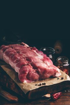 Raw pork loin joint on cutting board with different spices