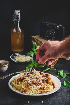 Spaghetti with bolognese sauce and grated parmesan cheese. Hand garnish ready meal with basil leafs