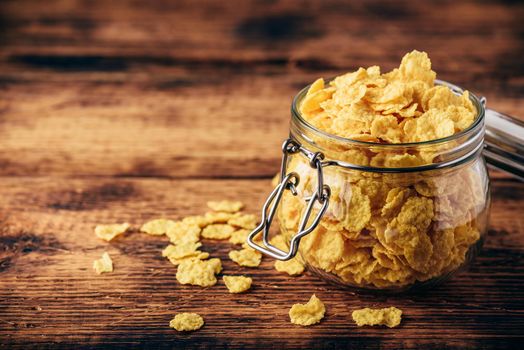 Jar full of corn flakes on a wooden surface