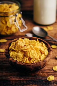 Corn flakes in a wooden bowl on rustic surface