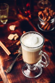 Coffee with Irish whiskey and whipped cream in glass on rustic wooden surface