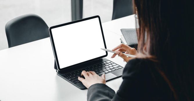 Cropped shot of a business woman sitting at modern office room and using blank screen digital tablet computer.
