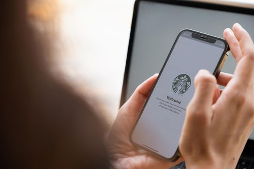 Chiang Mai, Thailand : JULY 17 2021 : Asian woman using Starbucks application for payment on iPhone screen in Starbucks coffee shop