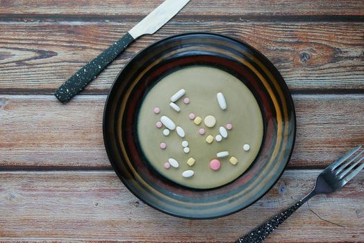 many colorful pills and capsules on plate on table .