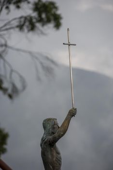Statue of Jesus on Mount Monserrate holding a cross with mountain and clouds in the background. El Senor Caido