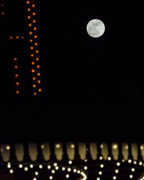 Full moon with party lights in the foreground.