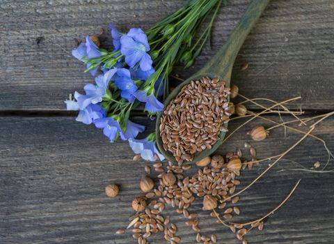 composition of flax flowers and suchara with seeds on rustic wooden background