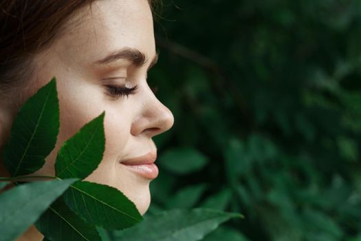 portrait of a woman skin care bare shoulders green leaves nature close-up. High quality photo