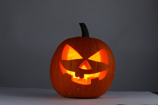 Jack o lantern Halloween pumpkin with carved funny face on gray background