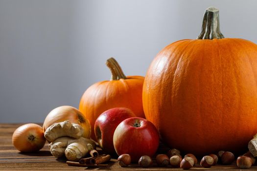 Autumn harvest still life with pumpkins, apples, hazelnut, corn on wooden background with copy space for text