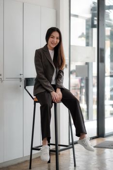 Portrait of attractive young asian woman in casual clothes smiling while looking into camera.