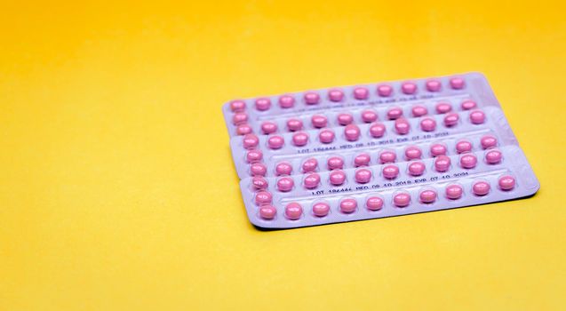 Blister packs of contraceptive pills on yellow background. Hormone pills for treatment hormone acne. Birth control pills. Estrogen and progesterone hormone pills. Pharmacy banner. Prescription drugs.