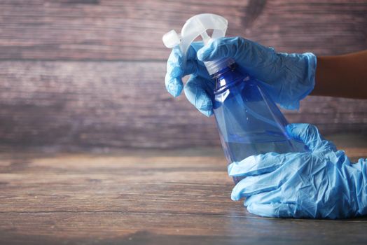hand in blue rubber gloves holding spray bottle with copy space, top view