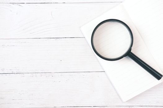 open book and magnifying glass on table