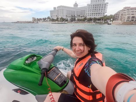 Woman making selfie photo while riding jet ski on Caribbean sea resort. Concept of having fun on summer vacation