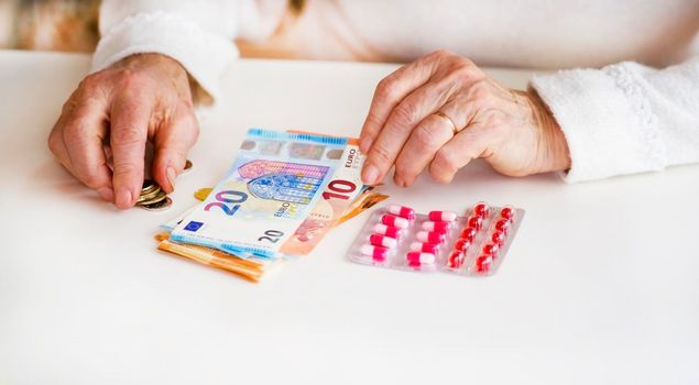 An older retired woman is counting money and saving it for medicines, medical treatment and insurance. Taking care of your health and wise investment.