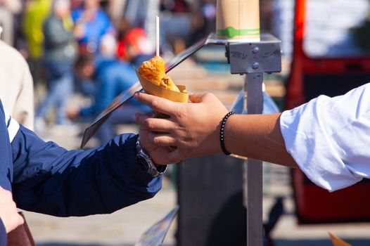 Close up of the hands of the shopkeeper who passes the potato croquettes to the buyer