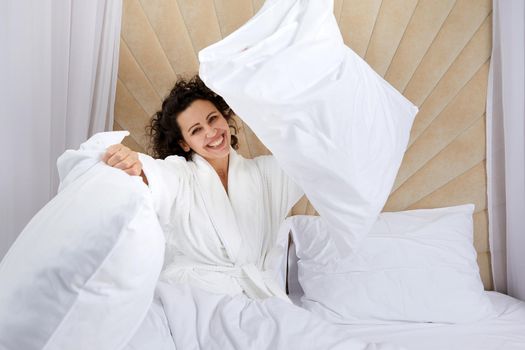 Playful woman throwing a pillow, Having fun on weekend at home