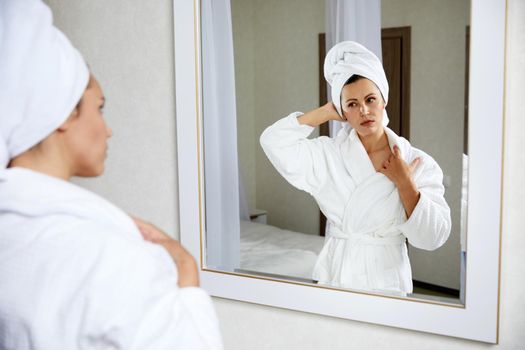 Young woman with hair wrapped in towel near mirror indoors