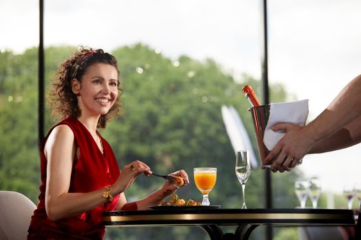 Bringing champagne in cooler with ice to young woman in restaurant