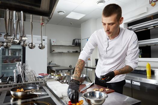 Professional chef cooking in the kitchen in hotel restaurant, preparing salad with shrimps