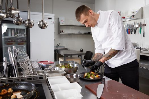 Close-up of chef hands preparing salad in a restaurant kitchen