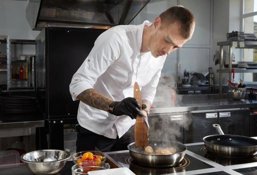 Professional chef cooking in the kitchen in hotel restaurant, preparing salad with shrimps