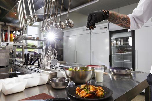 Close-up of chef hands preparing salad in a restaurant kitchen