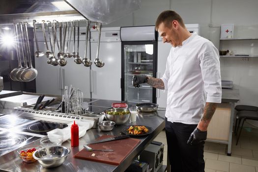 Professional chef cooking in the kitchen in hotel restaurant, preparing salad with shrimps