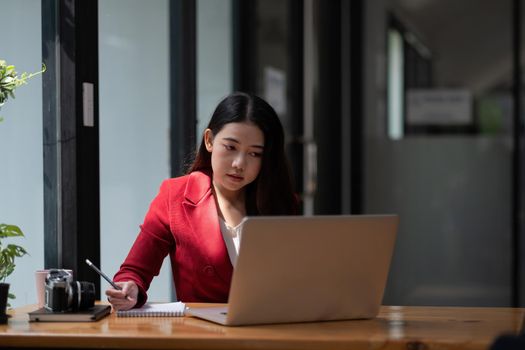 Asian business woman working on laptop computer and taking note at the office