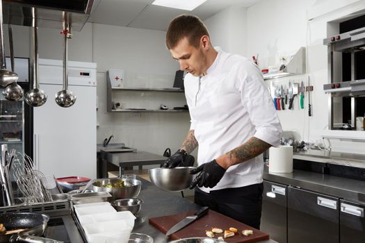 Professional chef cooking in the kitchen in hotel restaurant, preparing salad with shrimps