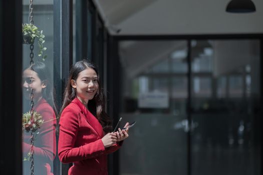 Image of young asian woman holding mobile phone while working in office
